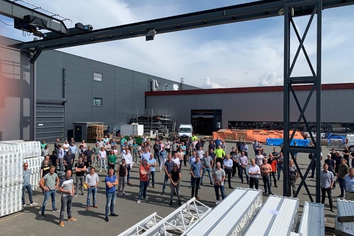 Het Van Der Hoeven-team staat samen buiten het bedrijfspand op een industrieterrein op een zonnige dag.