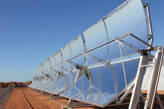 Row of large parabolic solar panels in a desert environment, used for turnkey greenhouse energy solutions.