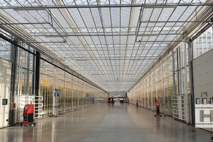 Interior view of Project Norby greenhouse with glass roof, modern structure, and spacious central aisle.
