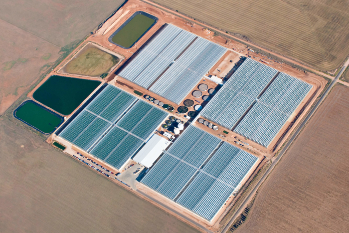 Aerial view of a large turnkey greenhouse facility in Australia, featuring glass-covered crop houses, water reservoirs, and advanced agricultural infrastructure.