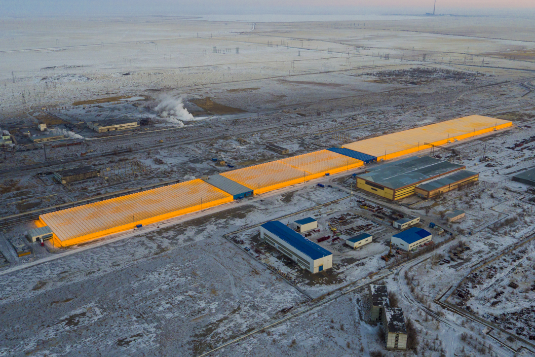 Aerial view of the Van Der Hoeven KAZ Ekibastuz II greenhouse complex glowing orange in the snowy Kazakh landscape.